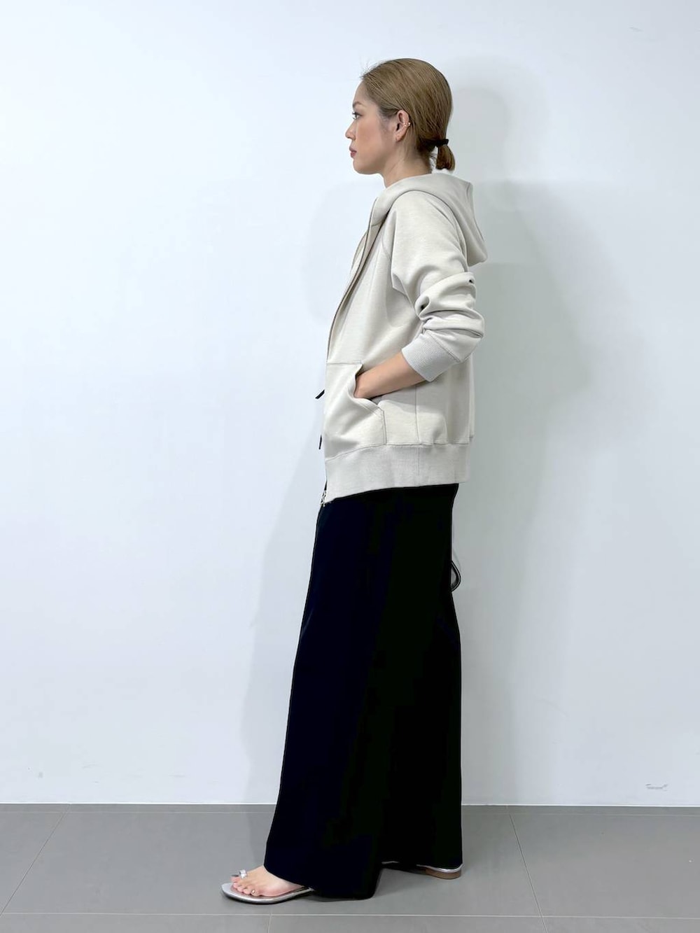 シルバー系のハンドバッグ、ベージュ系のパーカー、シルバー系のサンダルを着用したレディースの夏コーディネートの3枚目の写真