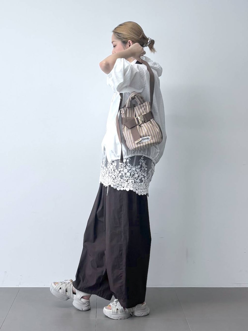 ブラウン系のその他パンツ、ベージュ系のショルダーバッグ、ホワイト系のブルゾンを着用したレディースの春コーディネートの4枚目の写真