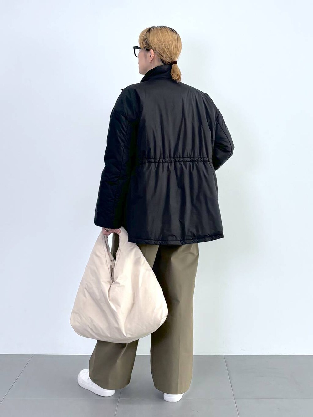 ブラック系のブルゾン、ホワイト系のスニーカー、グレー系のニット/セーターを着用したレディースの秋コーディネートの5枚目の写真