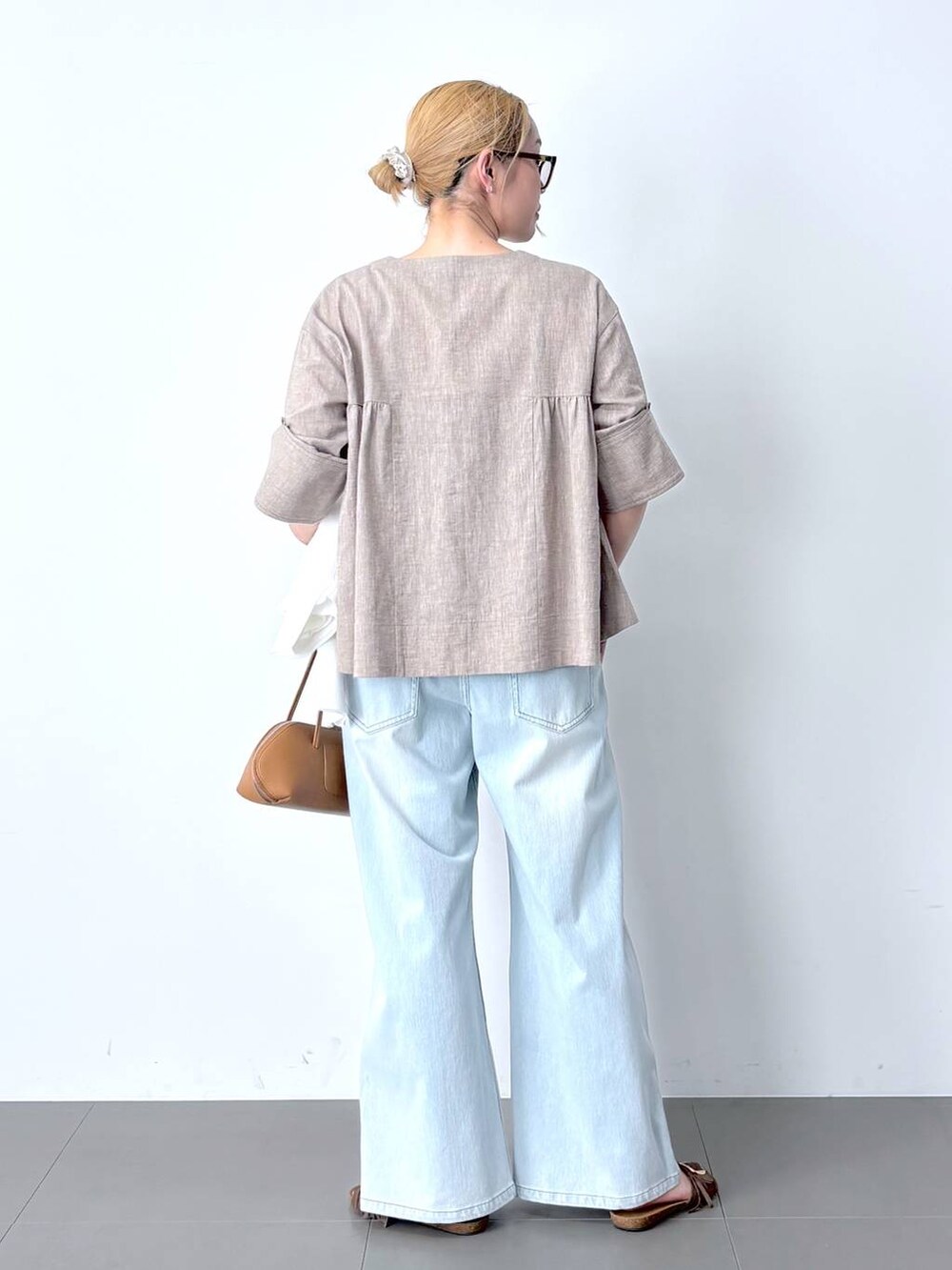 ブルー系のデニムパンツ、ベージュ系のシャツ/ブラウス、ブラウン系のハンドバッグを着用したレディースの春コーディネートの5枚目の写真