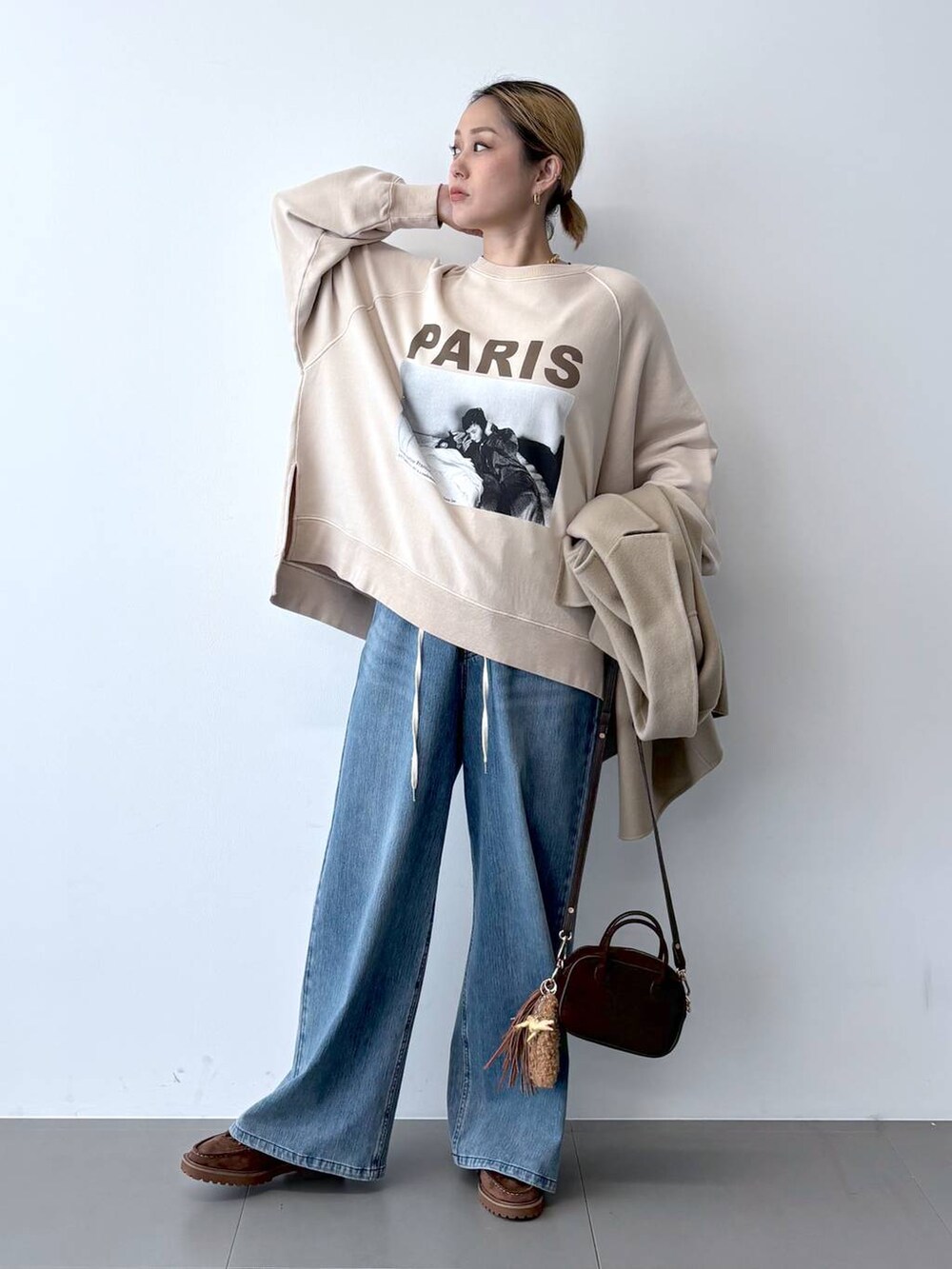 ブルー系のデニムパンツ、ベージュ系のベスト、ブラウン系のショルダーバッグを着用したレディースの秋コーディネートの6枚目の写真