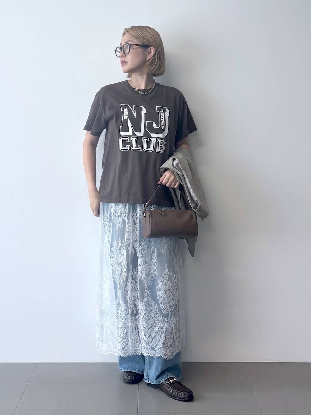 ブラウン系のハンドバッグ、ブラウン系のローファー、グレー系のTシャツ/カットソーを着用したレディースの夏コーディネートの5枚目の写真