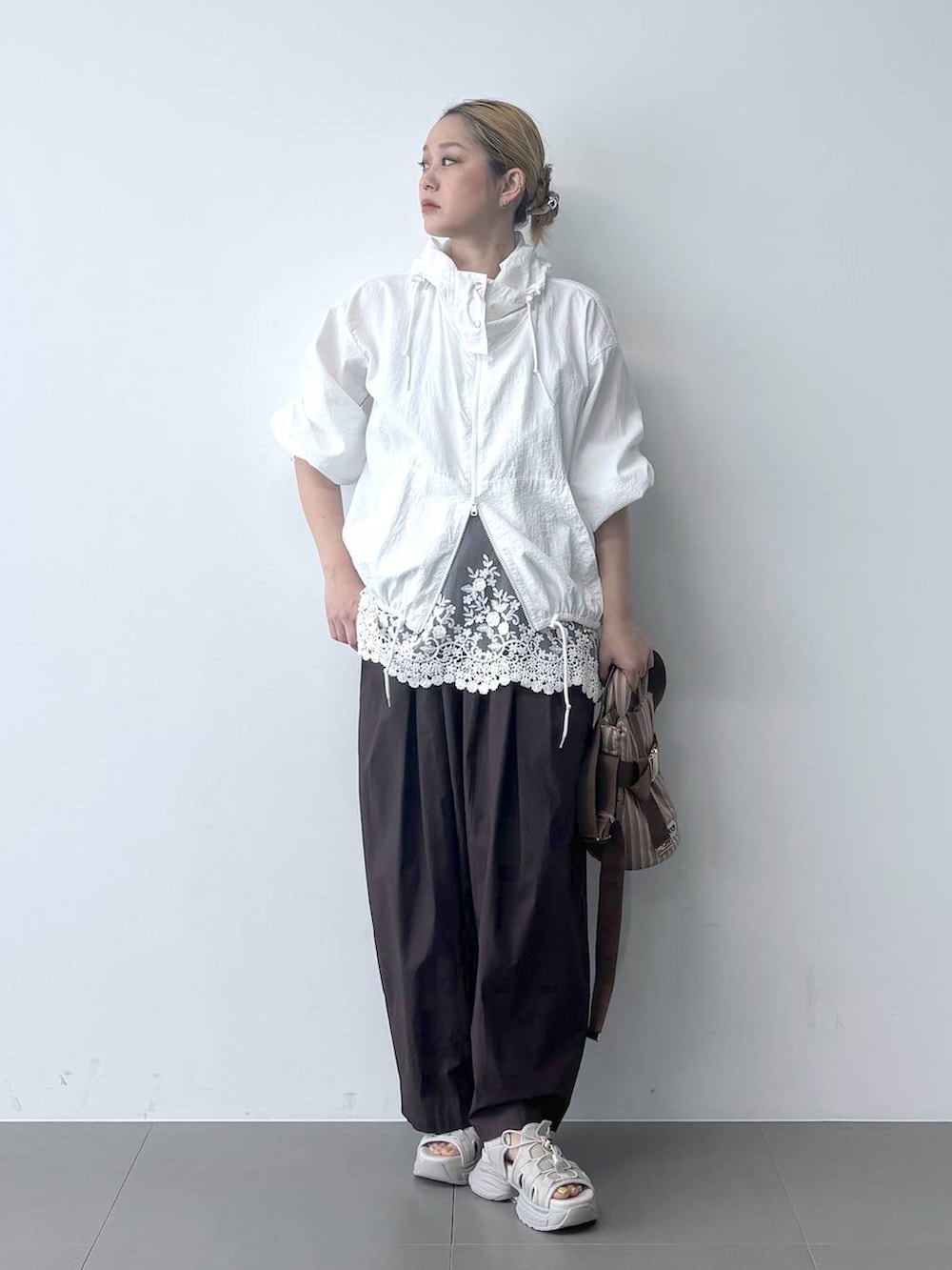 ブラウン系のその他パンツ、ベージュ系のショルダーバッグ、ホワイト系のブルゾンを着用したレディースの春コーディネートの2枚目の写真