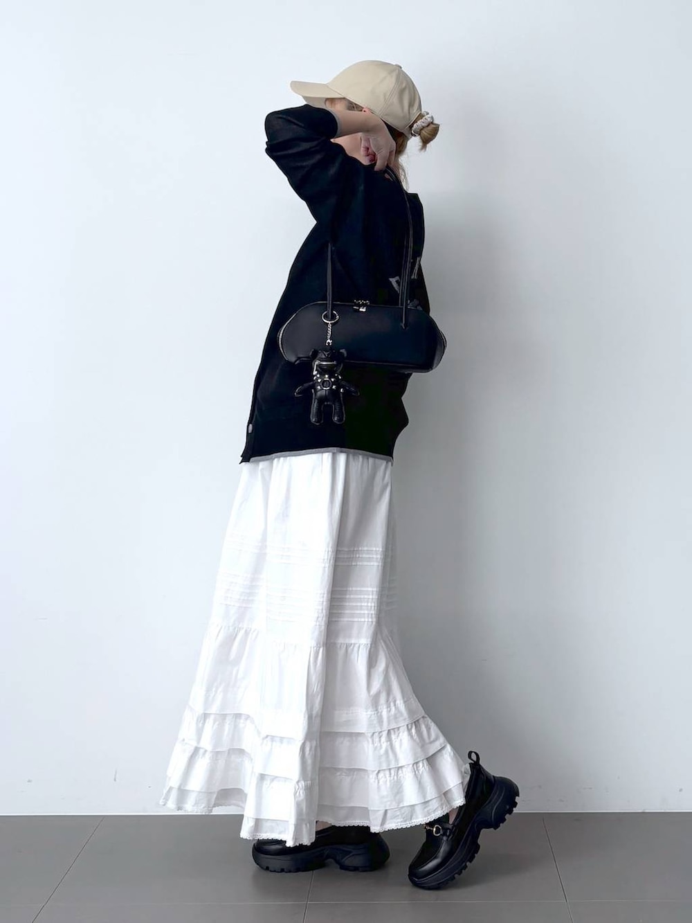 ホワイト系のTシャツ/カットソー、ホワイト系のスカート、ブラック系のハンドバッグを着用したレディースの春コーディネートの2枚目の写真