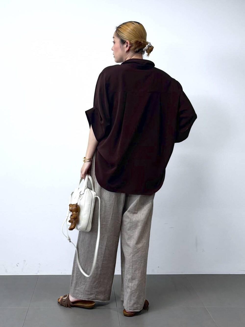 ベージュ系のその他パンツ、ブラウン系のシャツ/ブラウス、ホワイト系のショルダーバッグを着用したレディースの春コーディネートの5枚目の写真