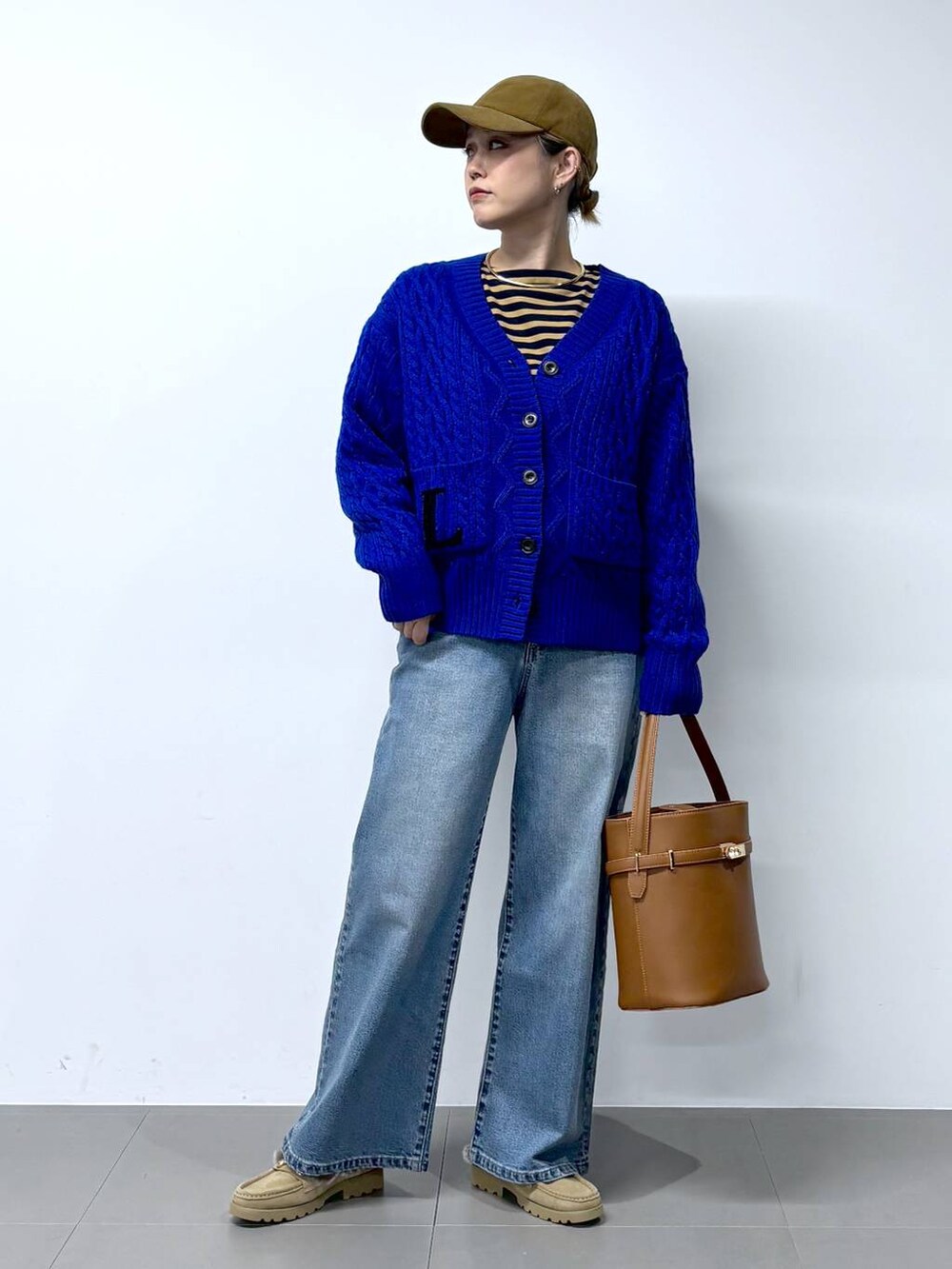 ブルー系のデニムパンツ、ベージュ系のTシャツ/カットソー、イエロー系のハンドバッグを着用したレディースの秋コーディネートの2枚目の写真