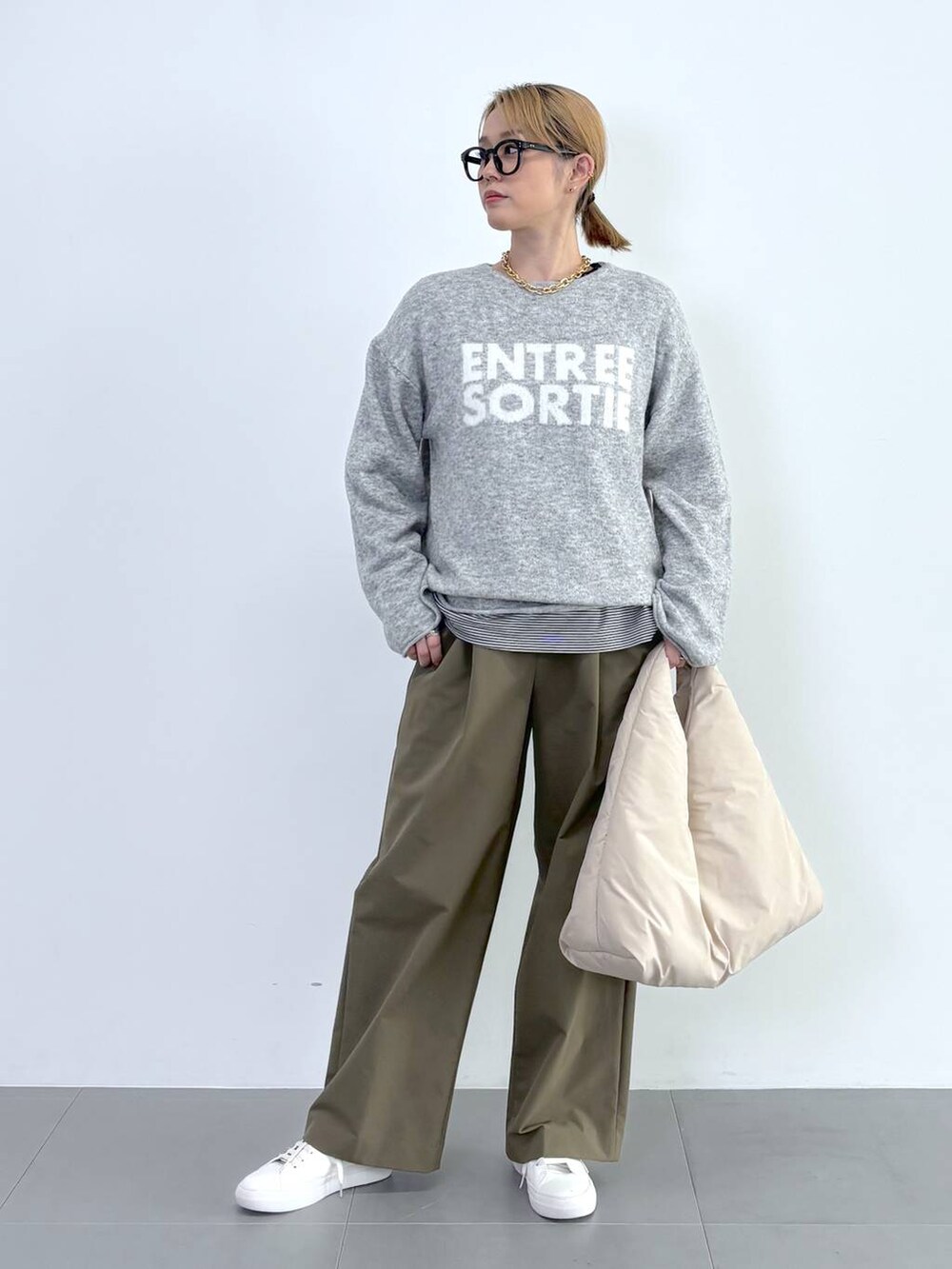 ブラック系のブルゾン、ホワイト系のスニーカー、グレー系のニット/セーターを着用したレディースの秋コーディネートの6枚目の写真