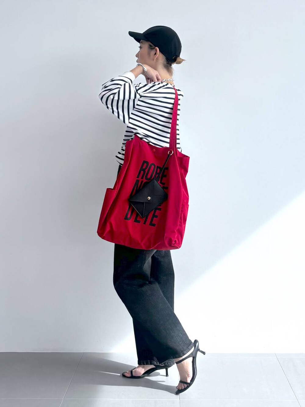 ブラック系のスリッポン、ホワイト系のTシャツ/カットソー、レッド系のトートバッグを着用したレディースの夏コーディネートの2枚目の写真