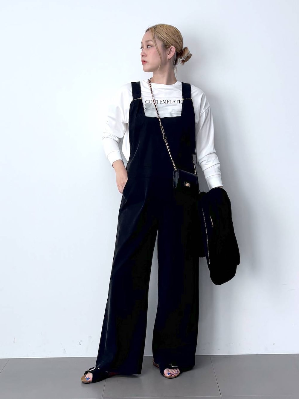 ブラック系のブルゾン、ホワイト系のTシャツ/カットソー、ブラック系のサロペット/オーバーオールを着用したレディースの春コーディネートの2枚目の写真