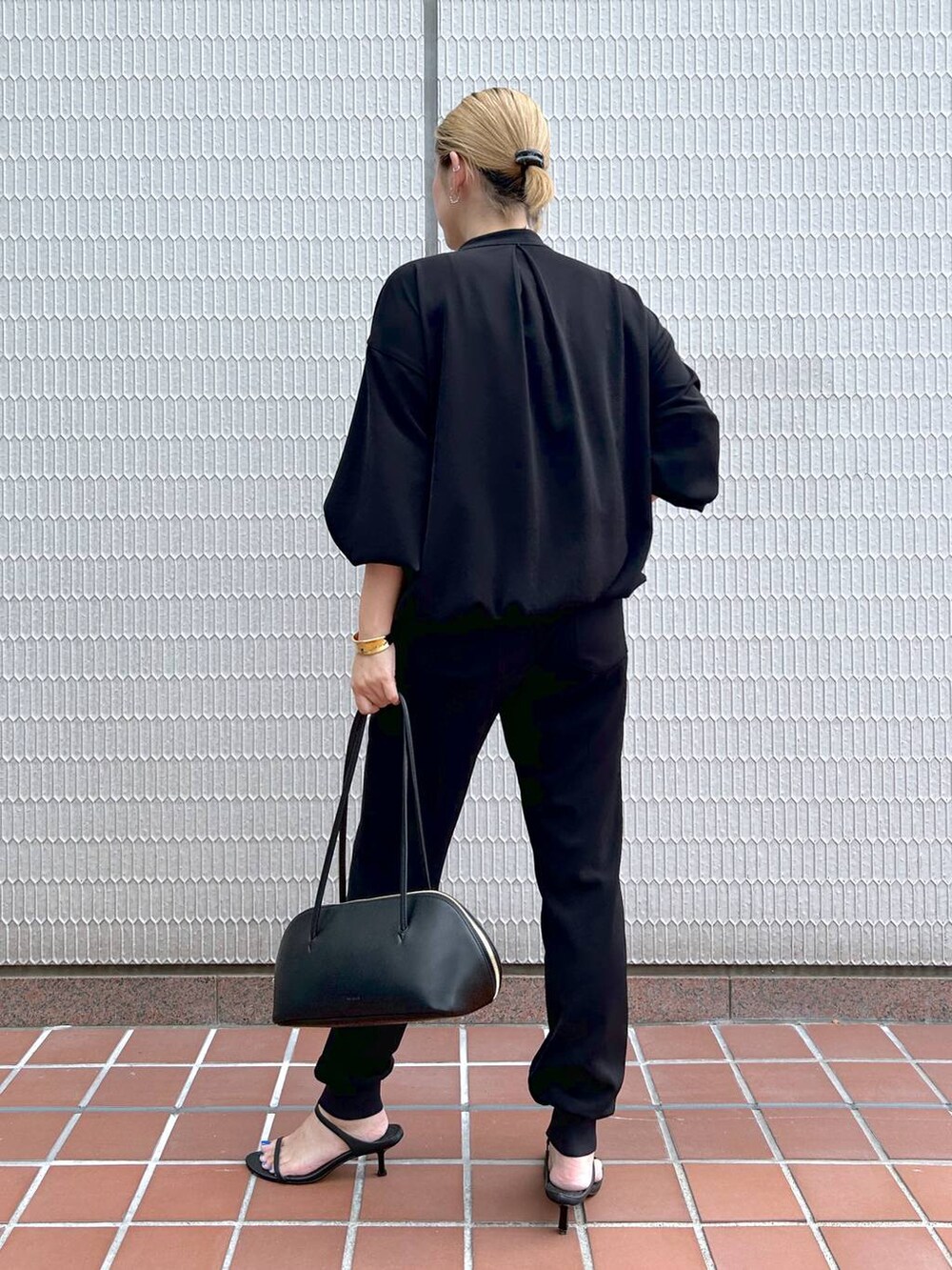 ブラック系のトートバッグ、ブラック系のブルゾン、ブラック系のサンダルを着用したレディースの秋コーディネートの4枚目の写真