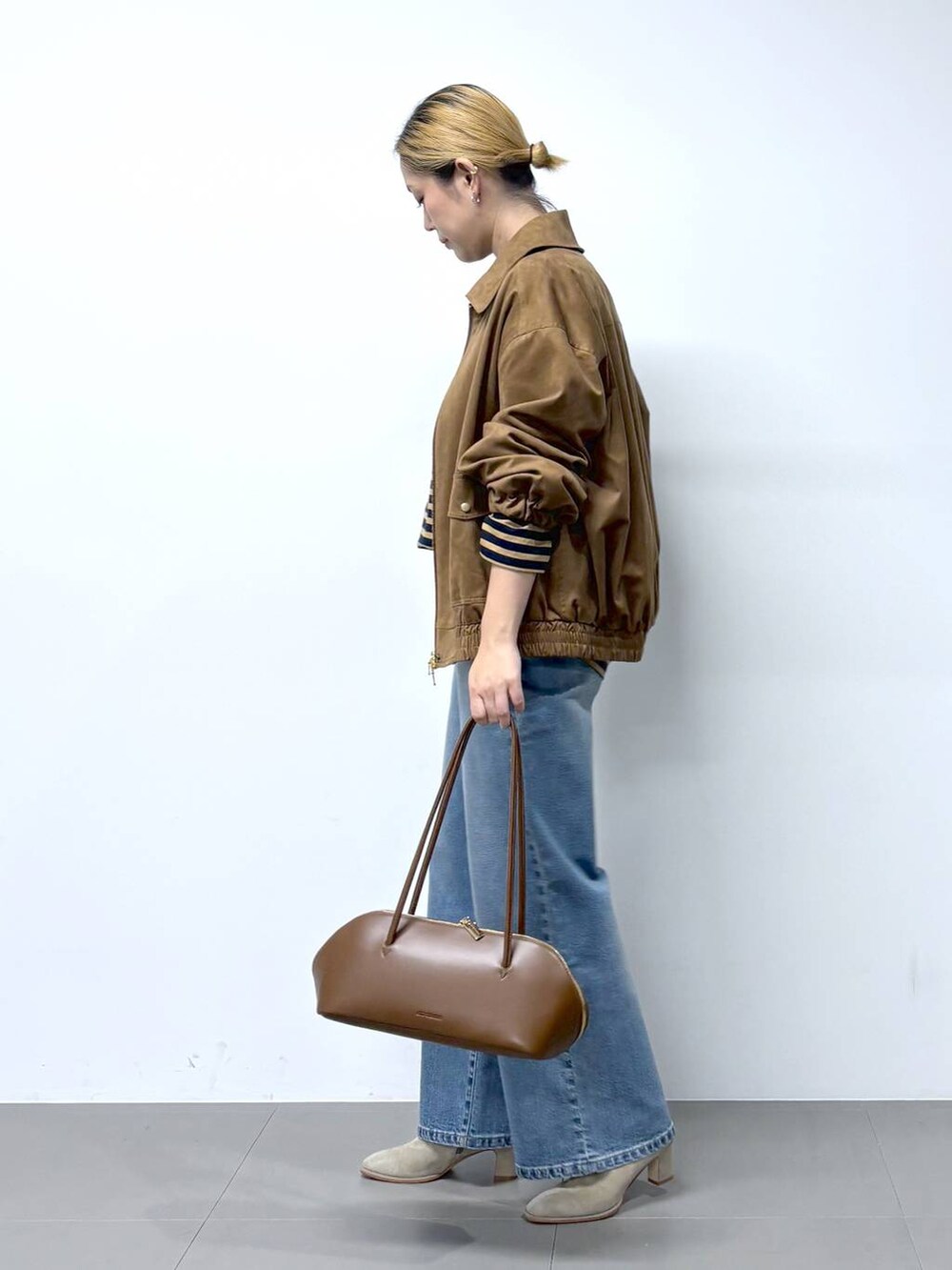 ブルー系のデニムパンツ、ブラウン系のトートバッグ、ベージュ系のTシャツ/カットソーを着用したレディースの秋コーディネートの3枚目の写真