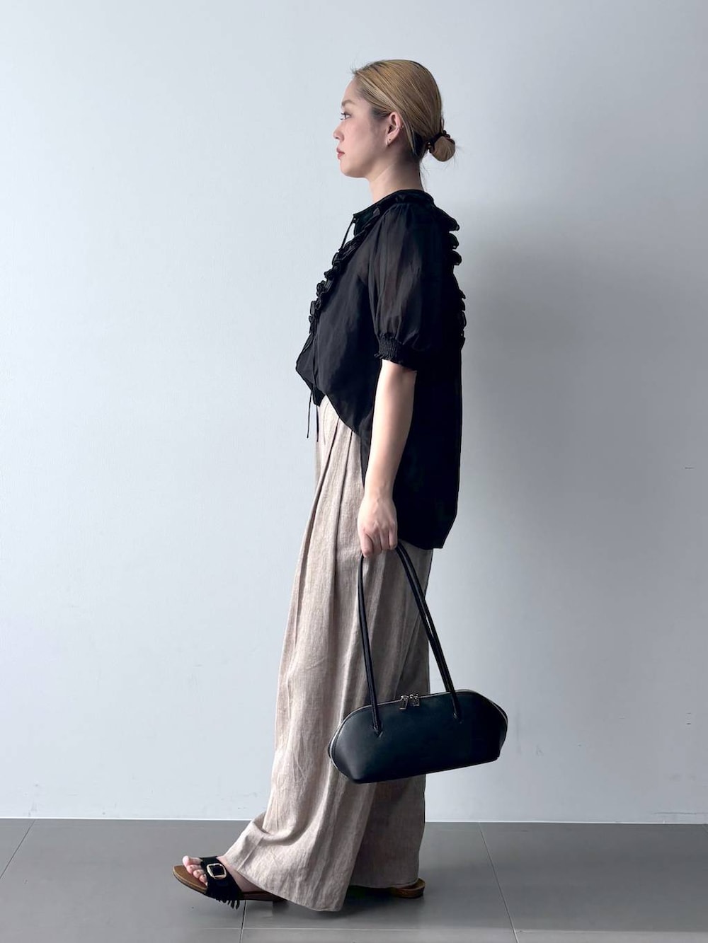 ベージュ系のその他パンツ、ブラック系のシャツ/ブラウス、ブラック系のハンドバッグを着用したレディースの春コーディネートの2枚目の写真