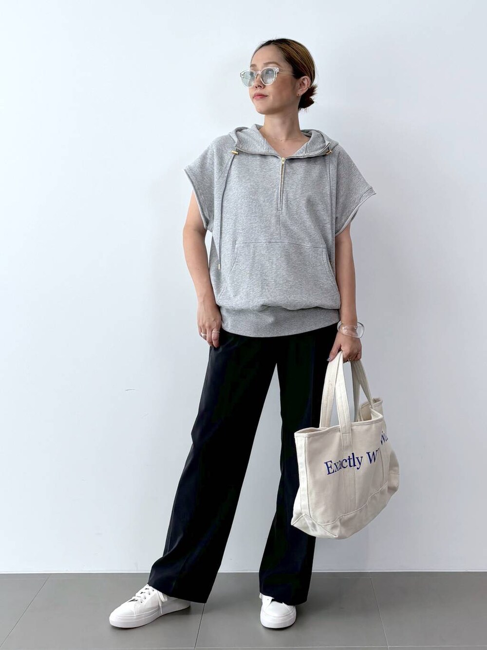 ホワイト系のトートバッグ、ホワイト系のスニーカー、ブラック系のスラックスを着用したレディースの夏コーディネートの2枚目の写真