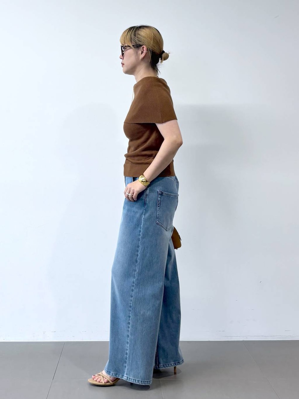 ブルー系のデニムパンツ、ベージュ系のサンダル、ブラウン系のニット/セーターを着用したレディースの夏コーディネートの2枚目の写真