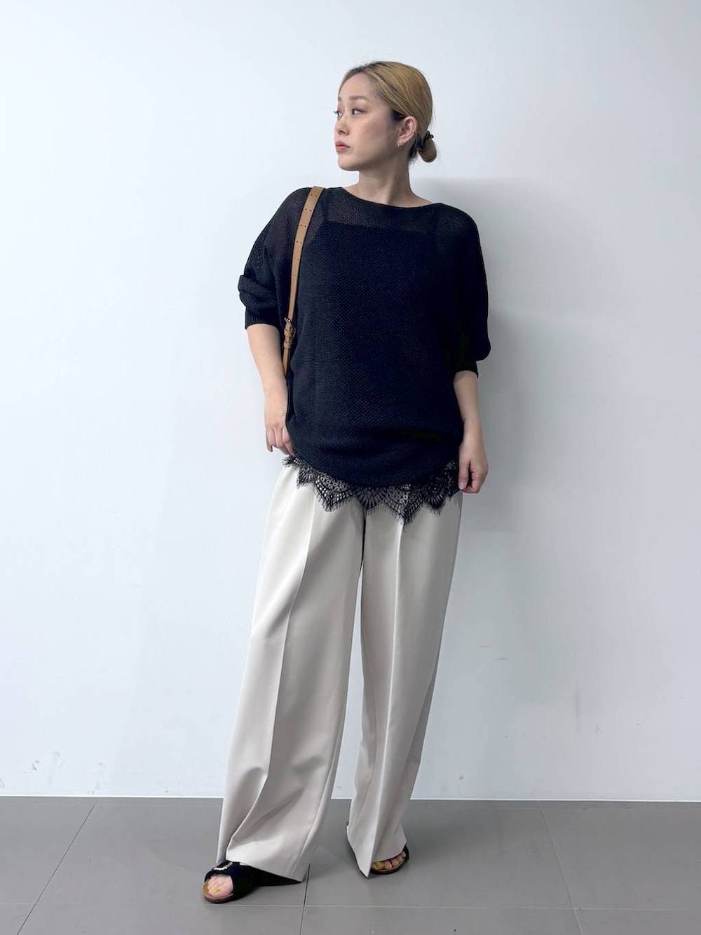 ブラック系のニット/セーター、ブラウン系のショルダーバッグ、グレー系のその他パンツを着用したレディースの春コーディネートの2枚目の写真