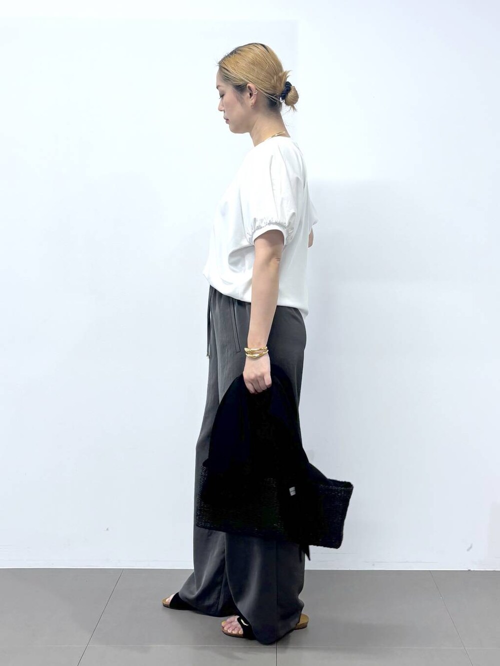 グレー系のその他パンツ、ホワイト系のTシャツ/カットソー、ブラック系のサンダルを着用したレディースの春コーディネートの6枚目の写真