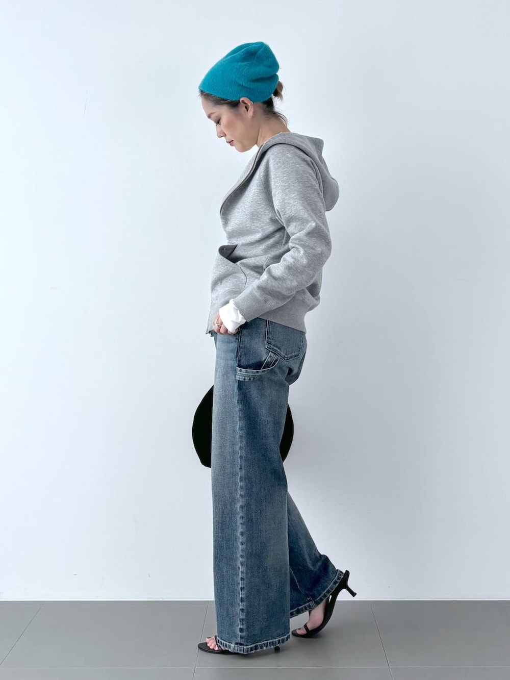 ブラック系のスリッポン、ブラック系のトートバッグ、ブルー系のデニムパンツを着用したレディースの秋コーディネートの4枚目の写真