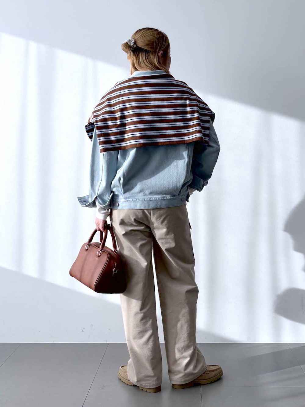 イエロー系のボストンバッグ、ホワイト系のTシャツ/カットソー、ベージュ系のローファーを着用したレディースの冬コーディネートの3枚目の写真