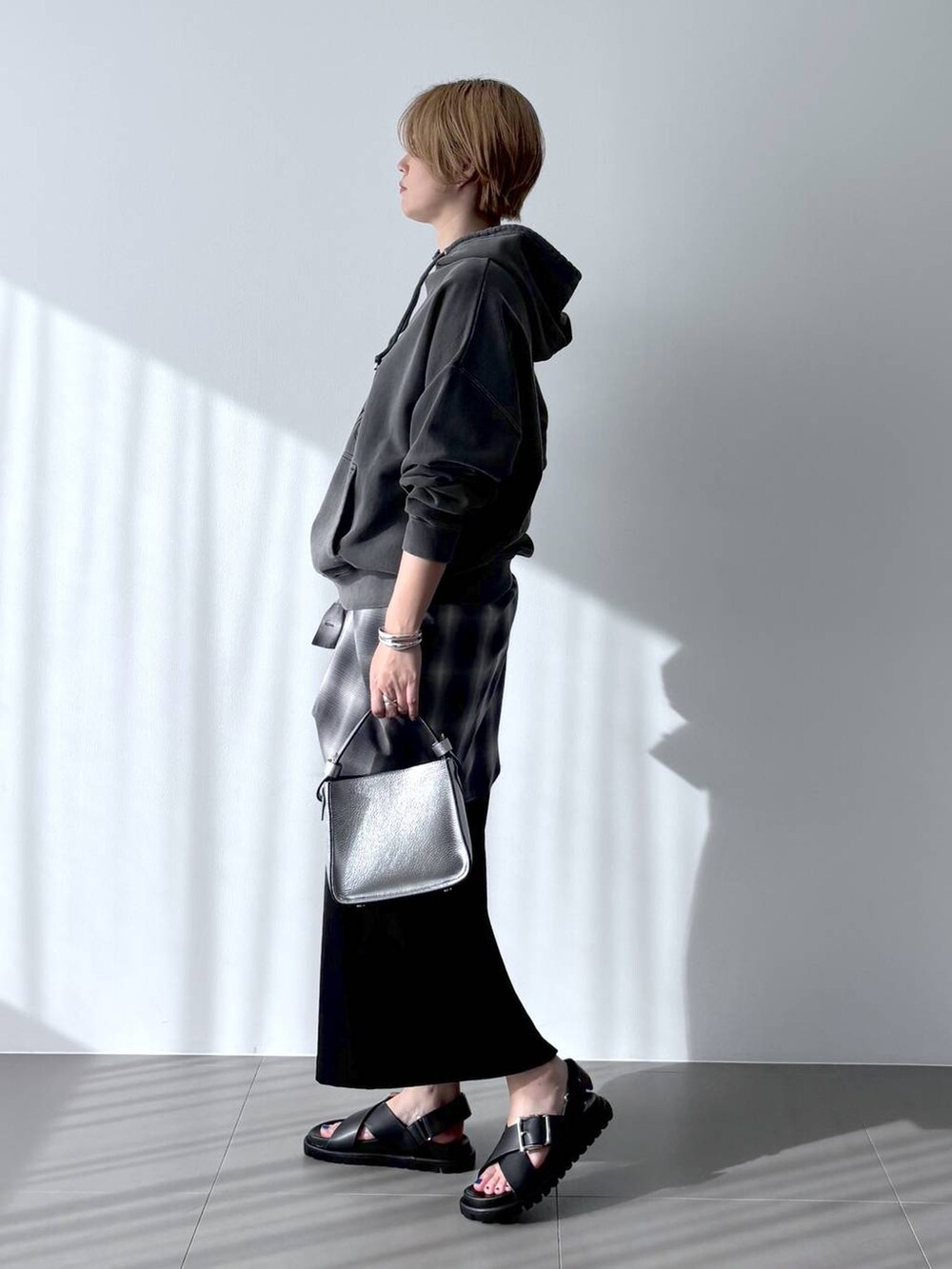シルバー系のハンドバッグ、グレー系のシャツ/ブラウス、ブラック系のスカートを着用したレディースの春コーディネートの2枚目の写真