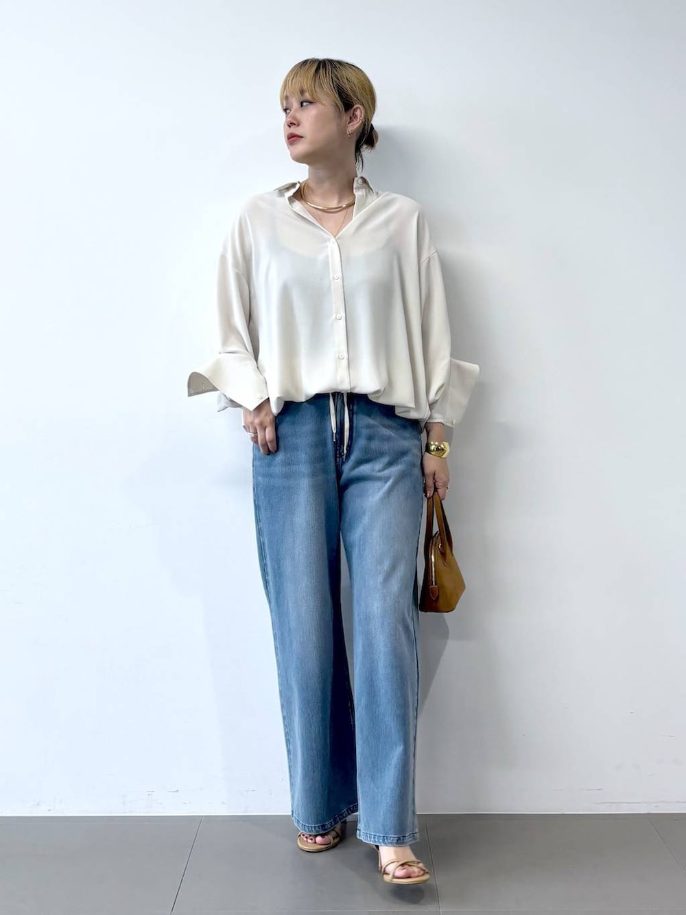 ブルー系のデニムパンツ、ベージュ系のサンダル、ホワイト系のシャツ/ブラウスを着用したレディースの夏コーディネートの2枚目の写真