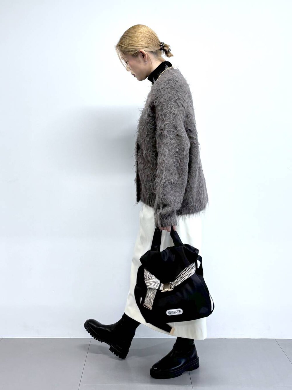 ブラック系のブーツ、ブラウン系のカーディガン/ボレロ、その他のショルダーバッグを着用したレディースの秋コーディネートの2枚目の写真