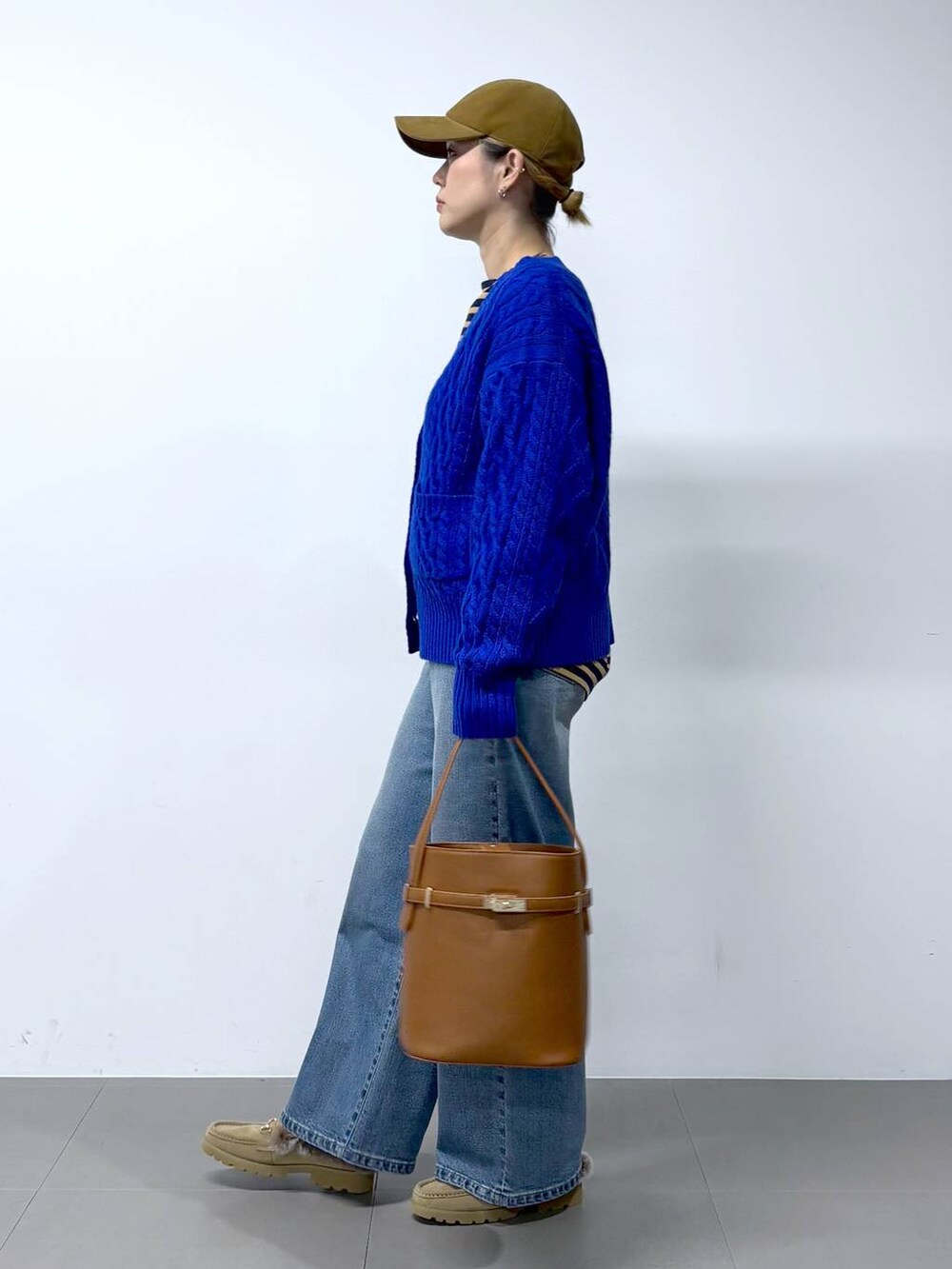 ブルー系のデニムパンツ、ベージュ系のTシャツ/カットソー、イエロー系のハンドバッグを着用したレディースの秋コーディネートの3枚目の写真