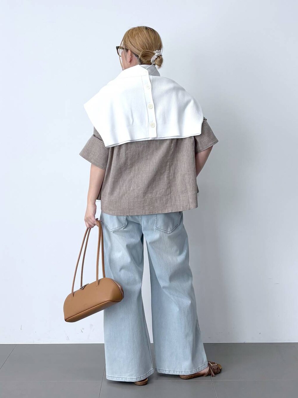 ブルー系のデニムパンツ、ベージュ系のシャツ/ブラウス、ブラウン系のハンドバッグを着用したレディースの春コーディネートの2枚目の写真