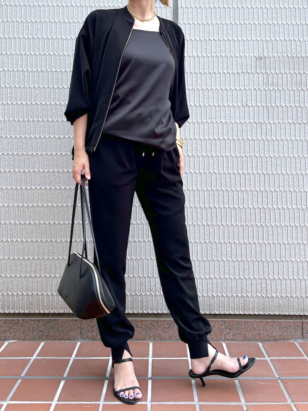 ブラック系のトートバッグ、ブラック系のブルゾン、ブラック系のサンダルを着用したレディースの秋コーディネートの5枚目の写真