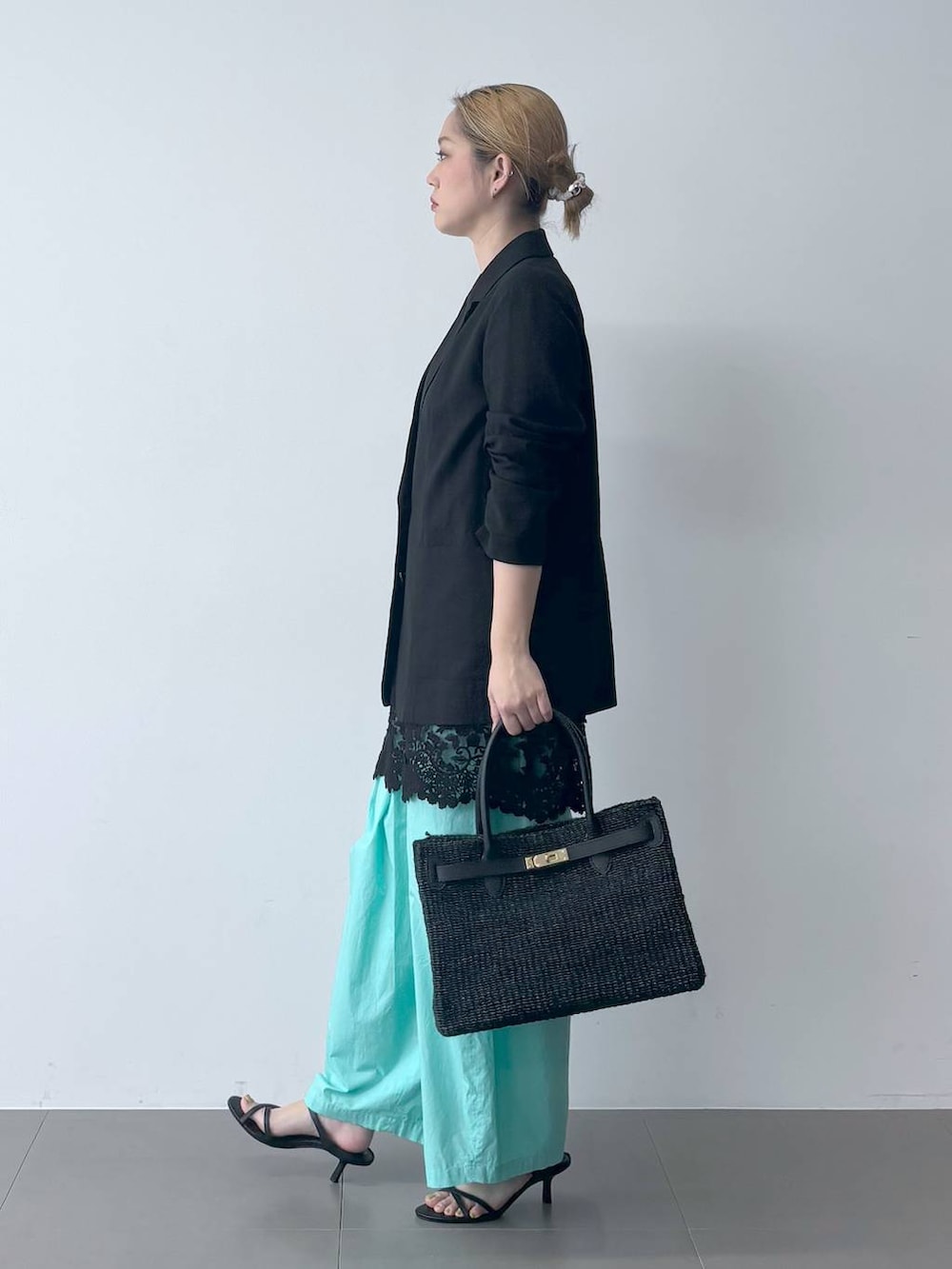 ブルー系のその他パンツ、ブラック系のテーラードジャケット、ブラック系のかごバッグを着用したレディースの春コーディネートの2枚目の写真