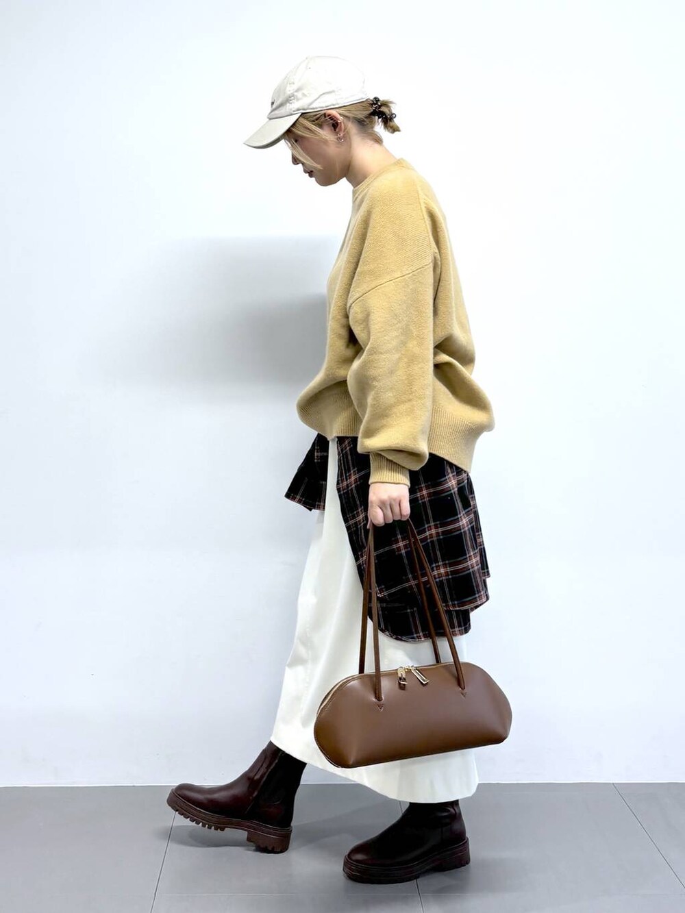 ブラウン系のトートバッグ、ホワイト系のスカート、ベージュ系のニット/セーターを着用したレディースの秋コーディネートの2枚目の写真
