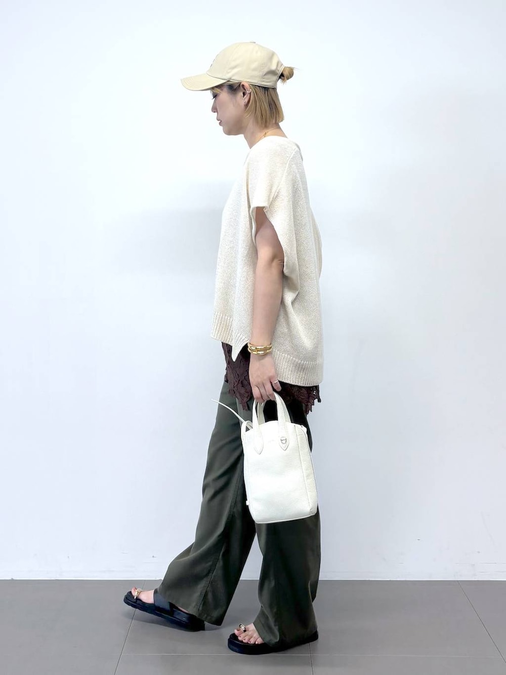 グリーン系のチノパンツ、ホワイト系のショルダーバッグ、ブラック系のサンダルを着用したレディースの夏コーディネートの2枚目の写真