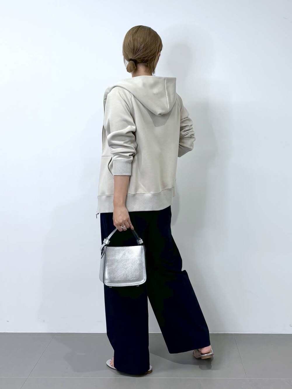 シルバー系のハンドバッグ、ベージュ系のパーカー、シルバー系のサンダルを着用したレディースの夏コーディネートの4枚目の写真