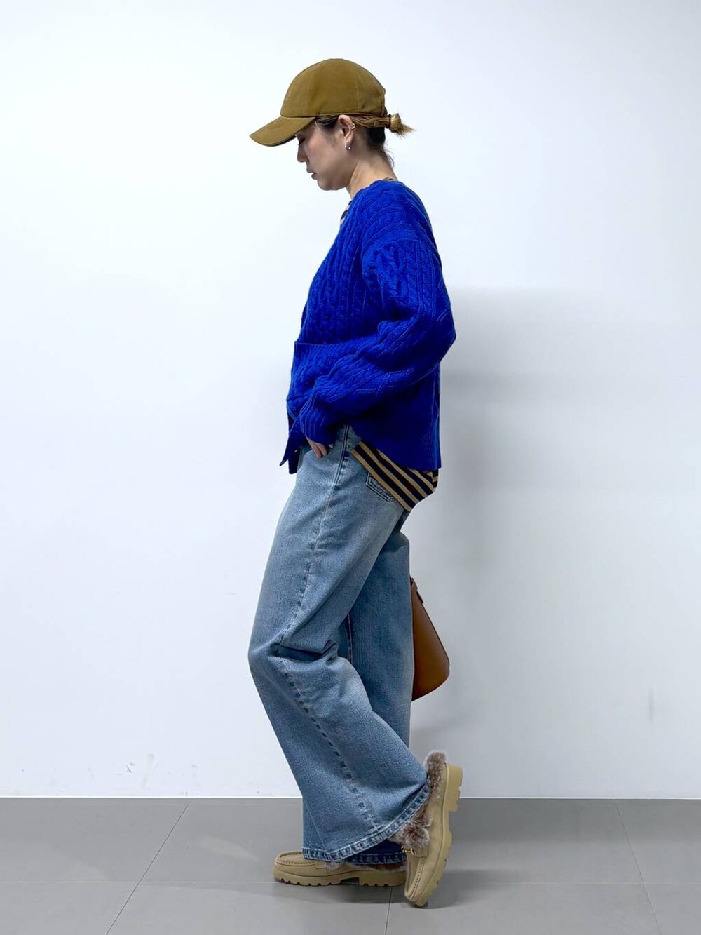 ブルー系のデニムパンツ、ベージュ系のTシャツ/カットソー、イエロー系のハンドバッグを着用したレディースの秋コーディネートの4枚目の写真