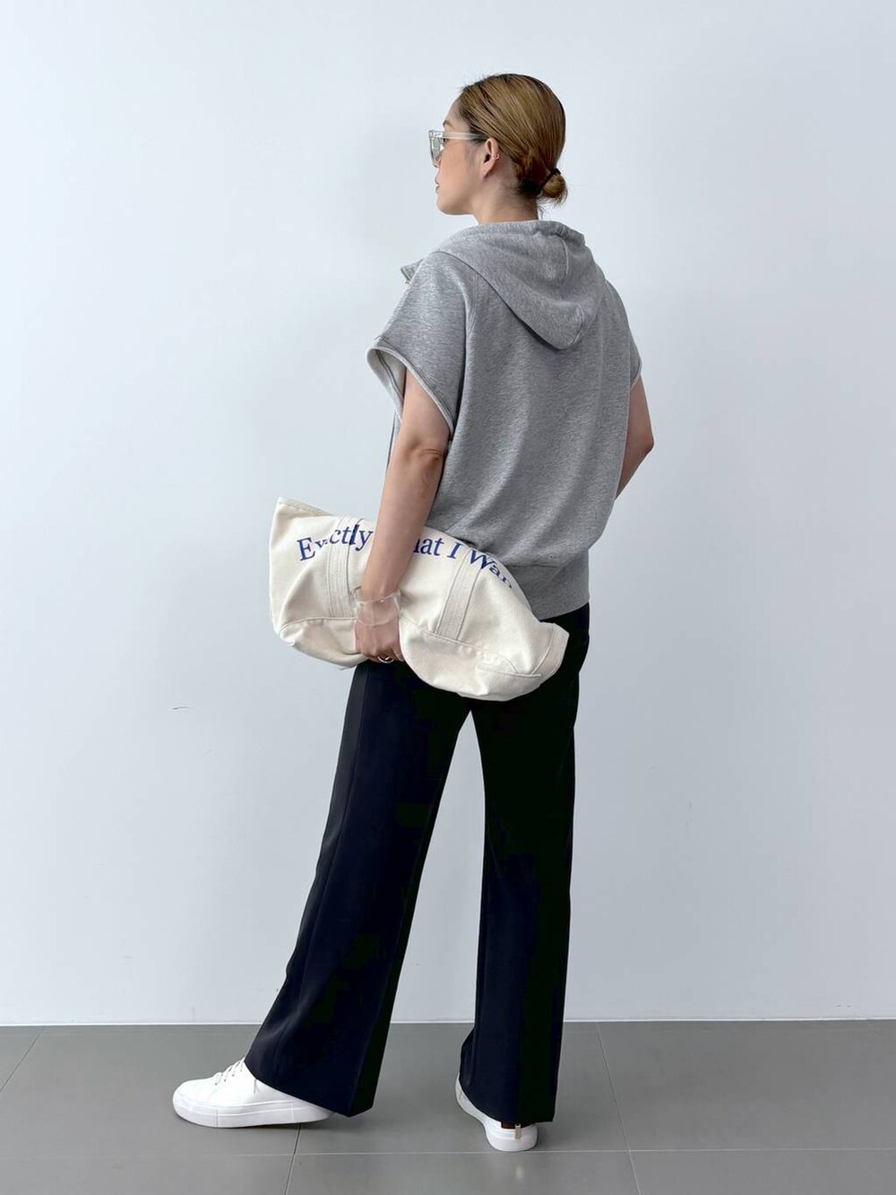 ホワイト系のトートバッグ、ホワイト系のスニーカー、ブラック系のスラックスを着用したレディースの夏コーディネートの4枚目の写真