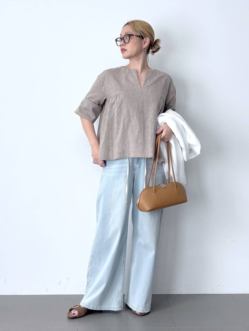 ブルー系のデニムパンツ、ベージュ系のシャツ/ブラウス、ブラウン系のハンドバッグを着用したレディースの春コーディネートの3枚目の写真
