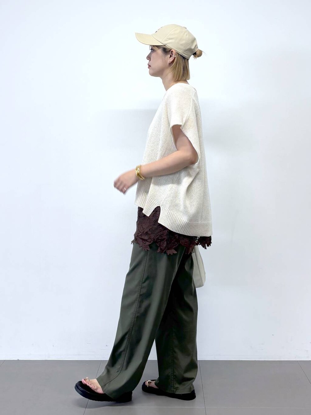 グリーン系のチノパンツ、ホワイト系のショルダーバッグ、ブラック系のサンダルを着用したレディースの夏コーディネートの3枚目の写真