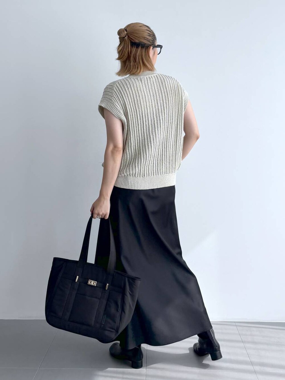 ブラック系のトートバッグ、ベージュ系のニット/セーター、ブラック系のスカートを着用したレディースの夏コーディネートの4枚目の写真