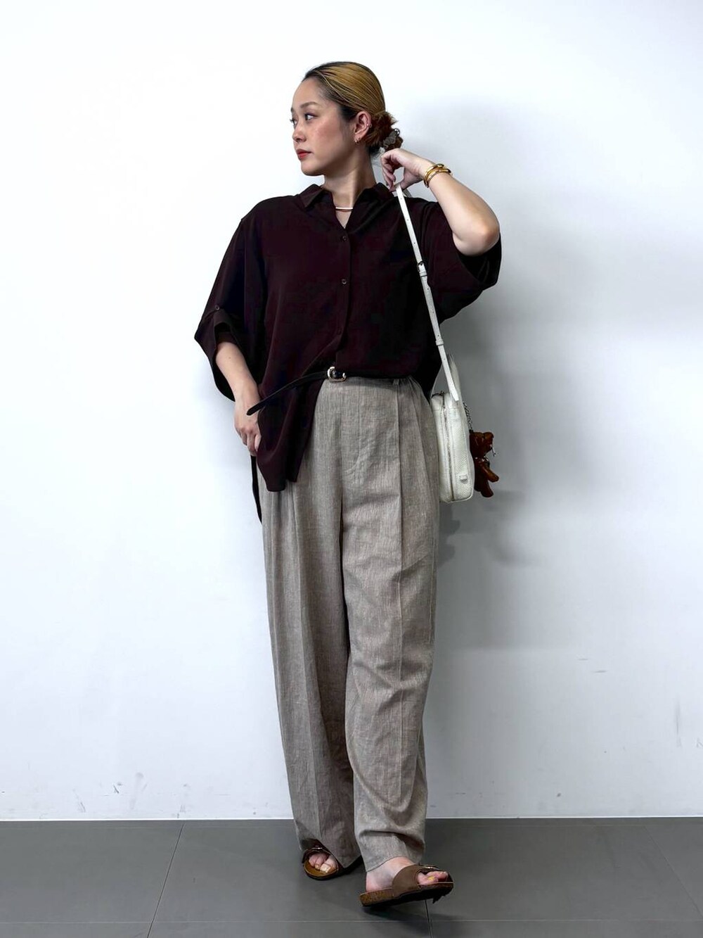 ベージュ系のその他パンツ、ブラウン系のシャツ/ブラウス、ホワイト系のショルダーバッグを着用したレディースの春コーディネートの2枚目の写真
