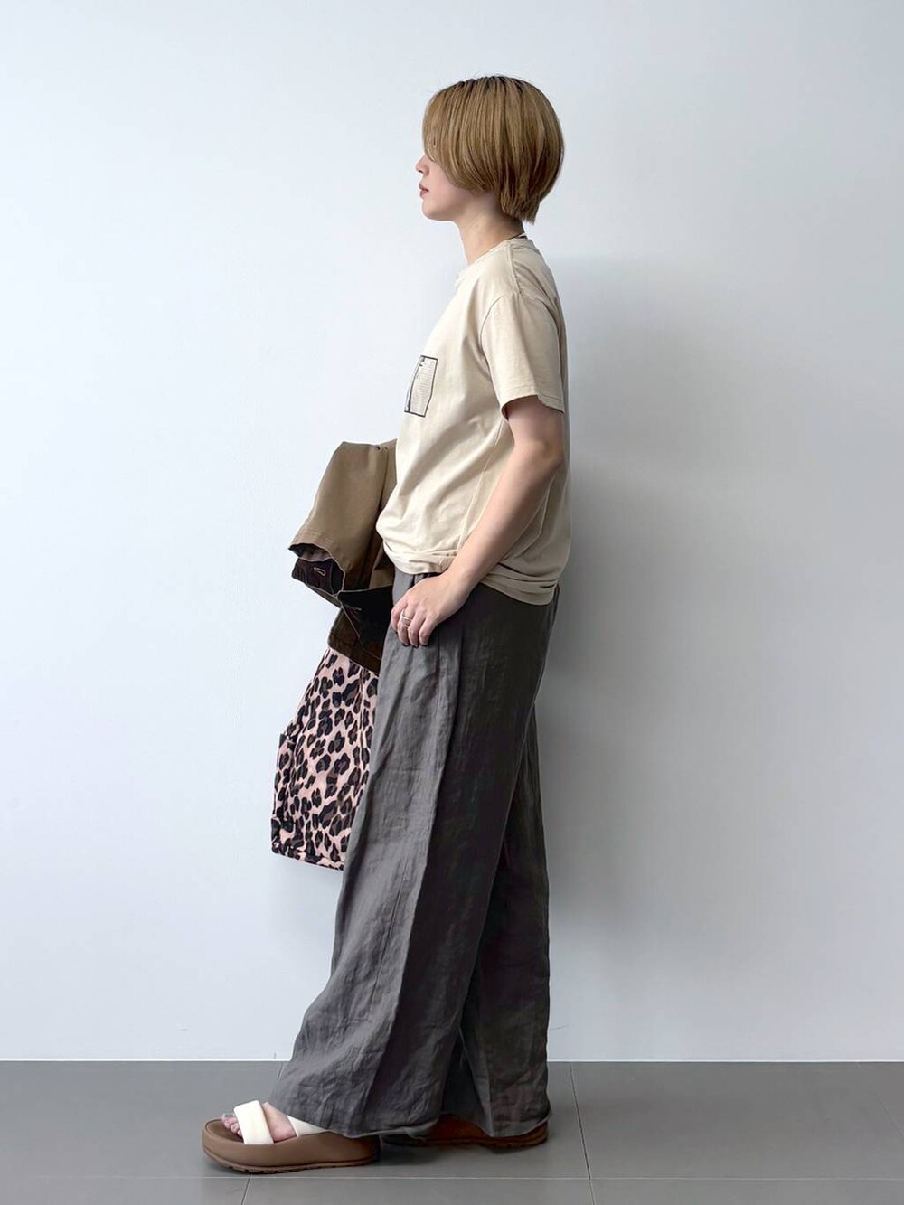 ベージュ系のミリタリージャケット、グリーン系のその他パンツ、その他のトートバッグを着用したレディースの春コーディネートの6枚目の写真