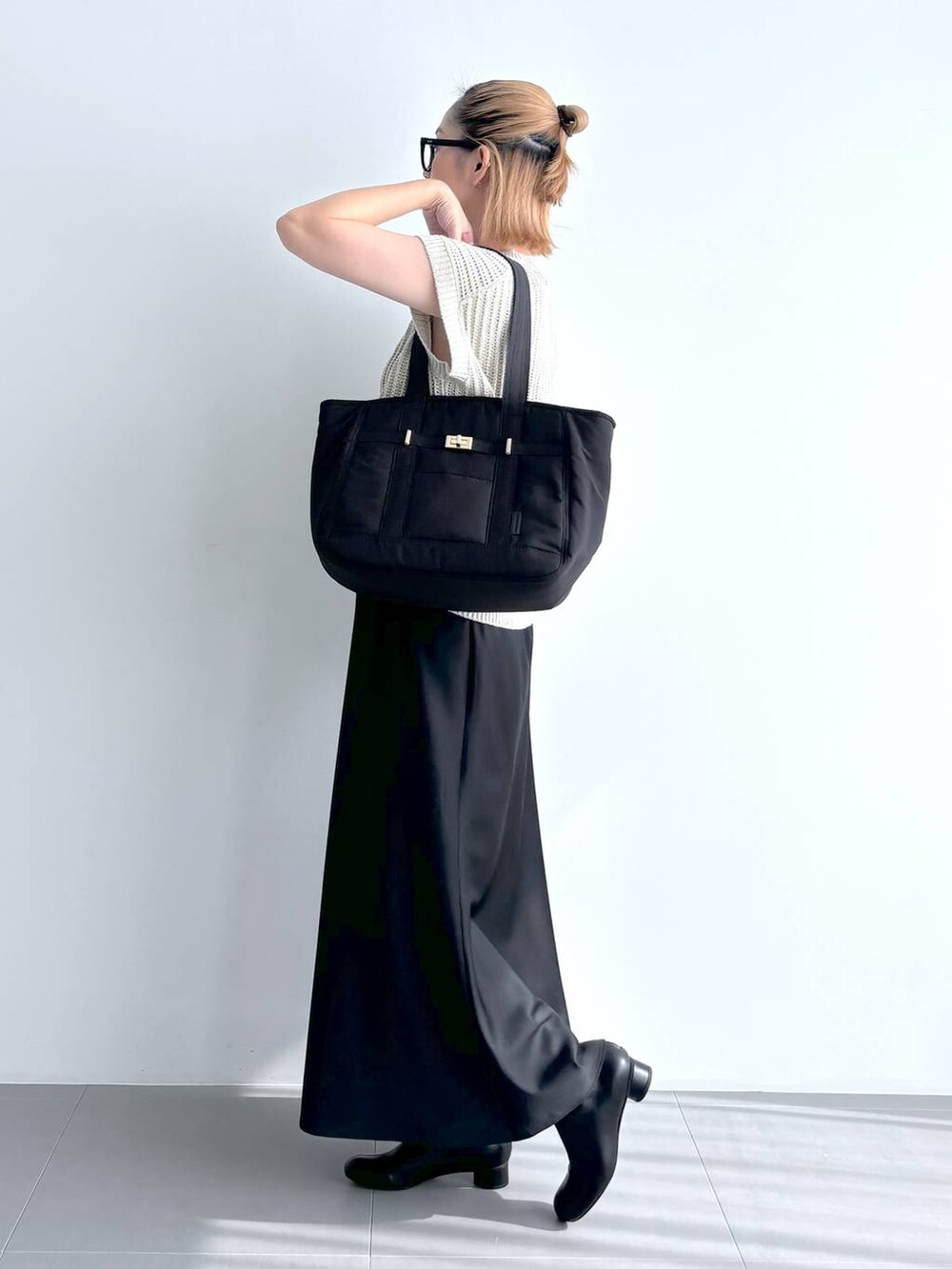 ブラック系のトートバッグ、ベージュ系のニット/セーター、ブラック系のスカートを着用したレディースの夏コーディネートの3枚目の写真