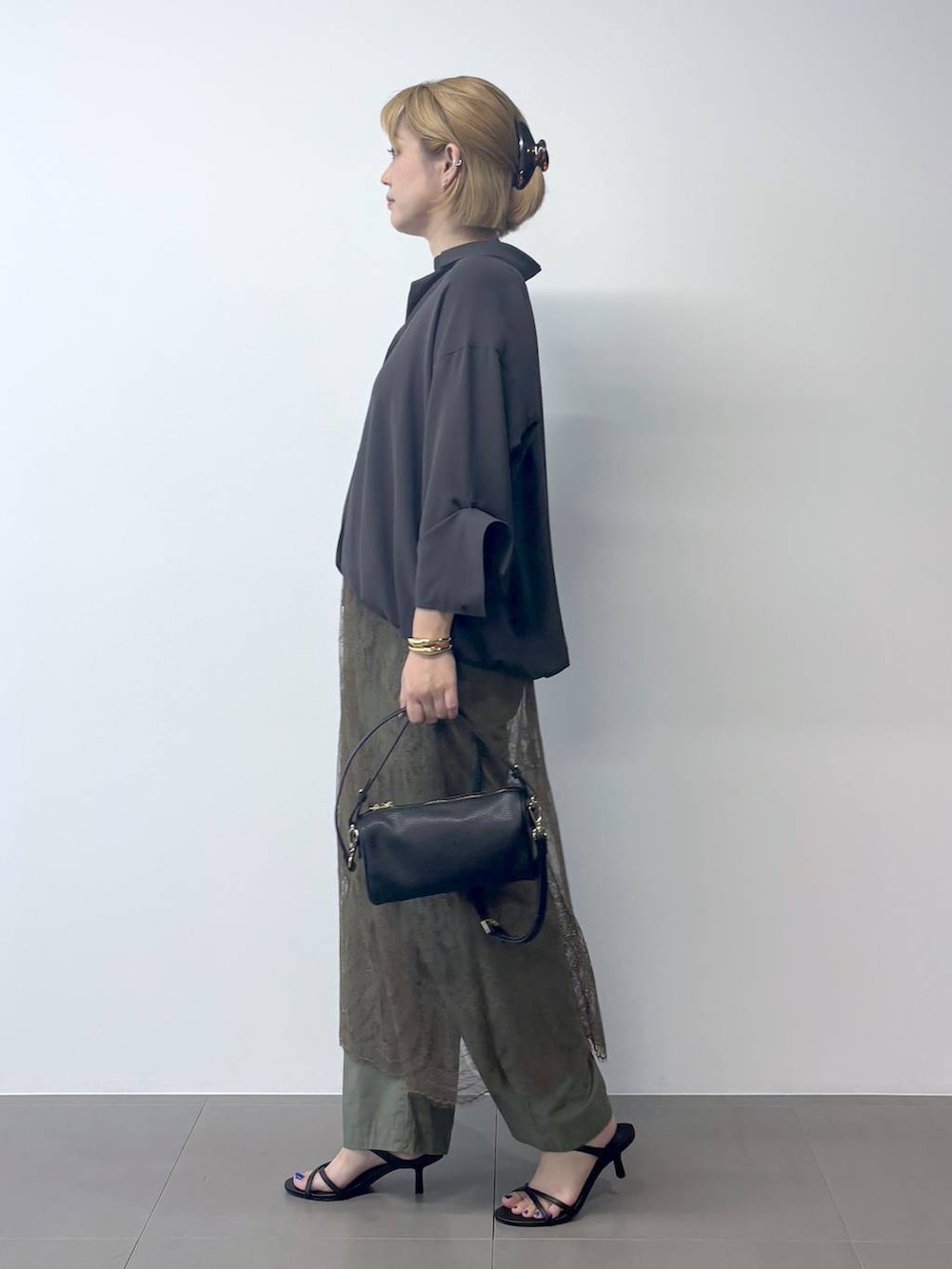ブラック系のハンドバッグ、ブラック系のサンダル、グリーン系のカーゴパンツを着用したレディースの夏コーディネートの3枚目の写真