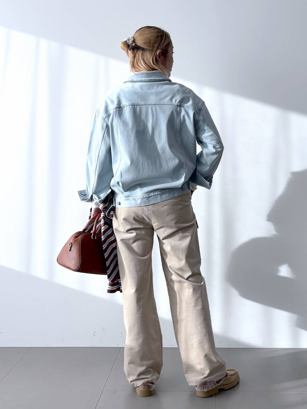 イエロー系のボストンバッグ、ホワイト系のTシャツ/カットソー、ベージュ系のローファーを着用したレディースの冬コーディネートの5枚目の写真