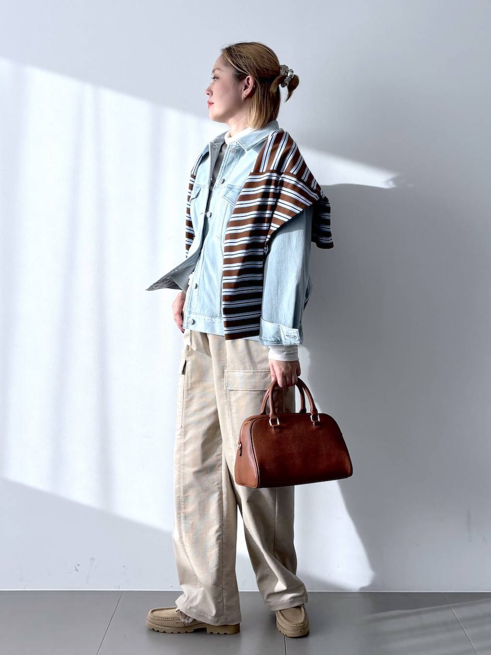 イエロー系のボストンバッグ、ホワイト系のTシャツ/カットソー、ベージュ系のローファーを着用したレディースの冬コーディネートの2枚目の写真