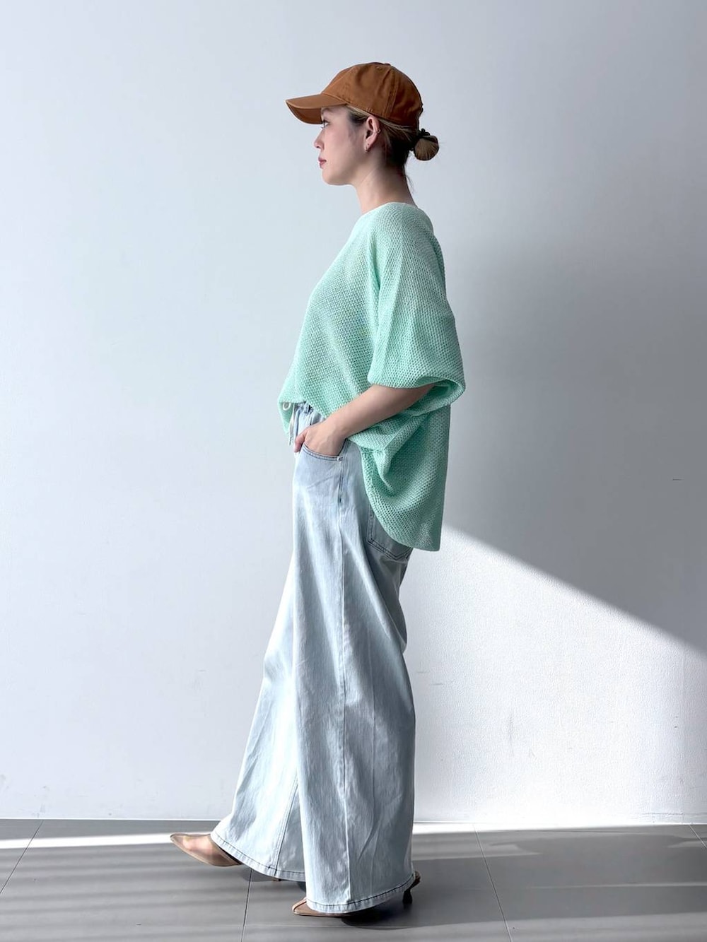 ブルー系のデニムパンツ、グリーン系のニット/セーター、ブラウン系のショルダーバッグを着用したレディースの春コーディネートの4枚目の写真