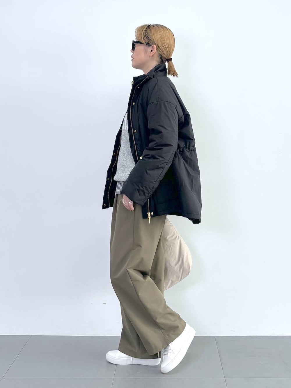 ブラック系のブルゾン、ホワイト系のスニーカー、グレー系のニット/セーターを着用したレディースの秋コーディネートの4枚目の写真