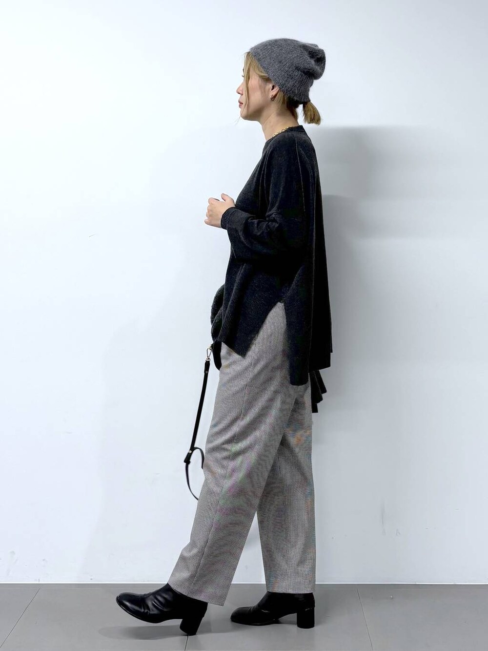 ブラック系のショルダーバッグ、ブラック系のブーツ、グレー系のニット/セーターを着用したレディースの秋コーディネートの4枚目の写真