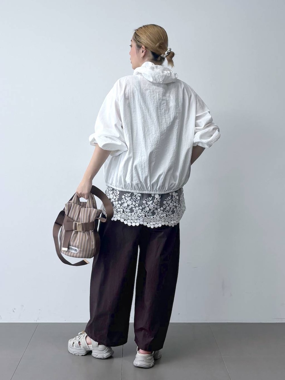 ブラウン系のその他パンツ、ベージュ系のショルダーバッグ、ホワイト系のブルゾンを着用したレディースの春コーディネートの5枚目の写真