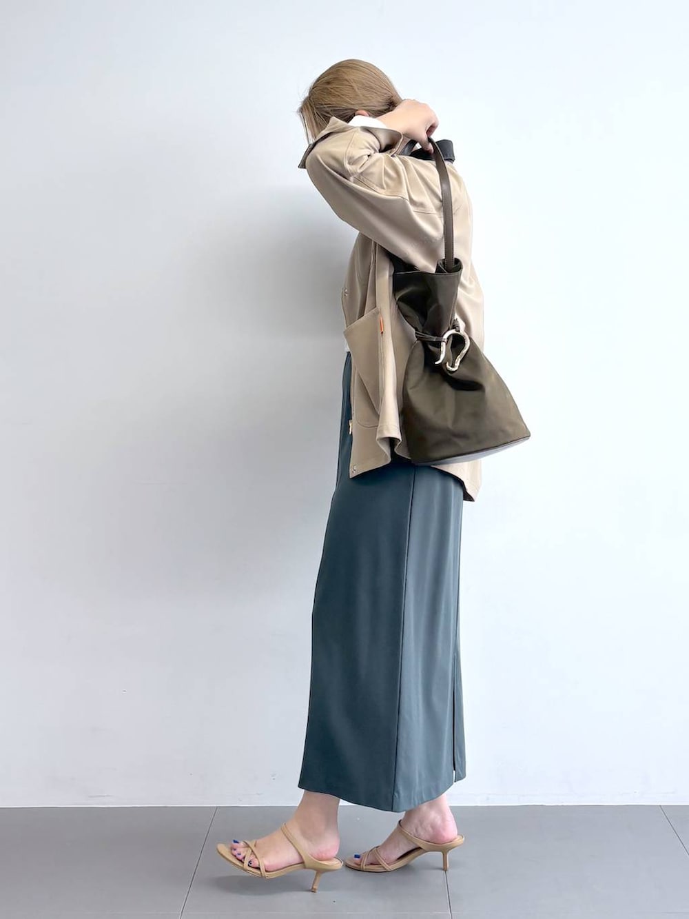 ホワイト系のTシャツ/カットソー、グリーン系のスカート、ベージュ系のカバーオールを着用したレディースの冬コーディネートの2枚目の写真