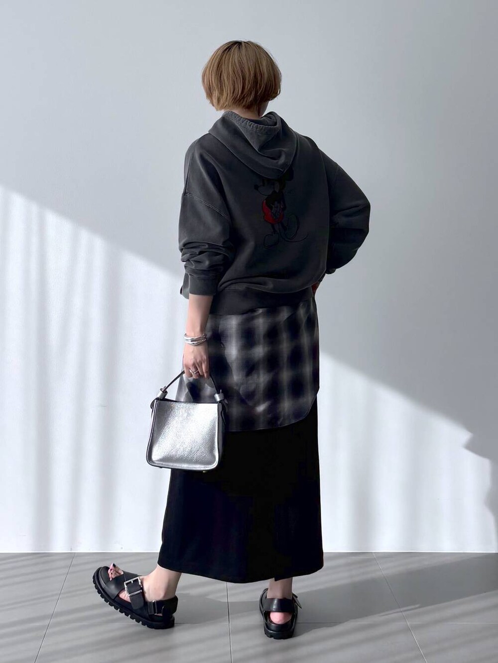 シルバー系のハンドバッグ、グレー系のシャツ/ブラウス、ブラック系のスカートを着用したレディースの春コーディネートの4枚目の写真