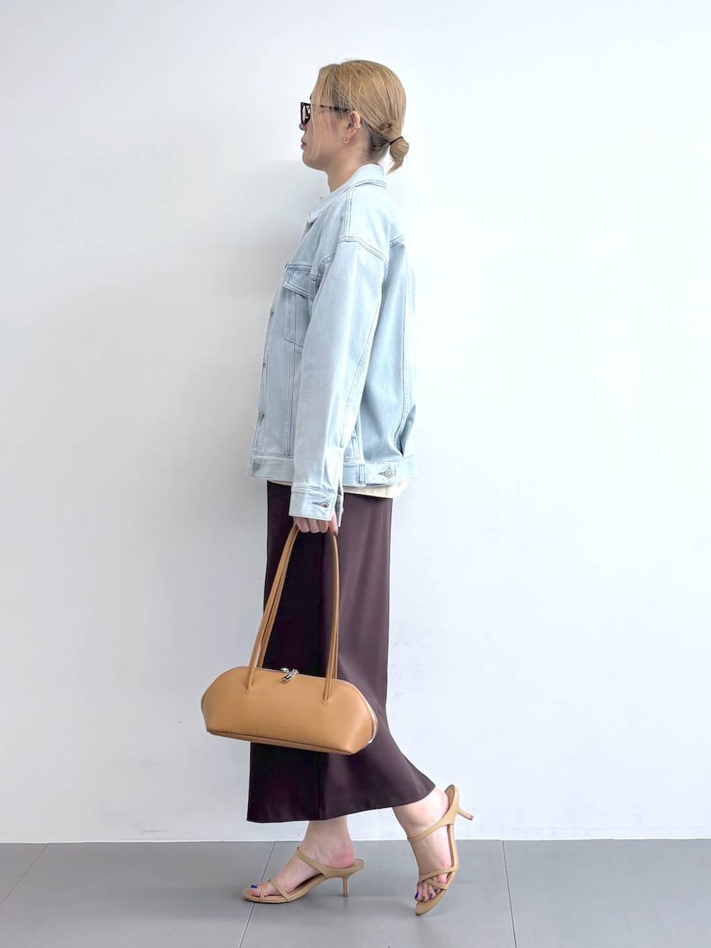 ブルー系のデニムジャケット、ブラウン系のスカート、ブラウン系のサングラスを着用したレディースの冬コーディネートの2枚目の写真